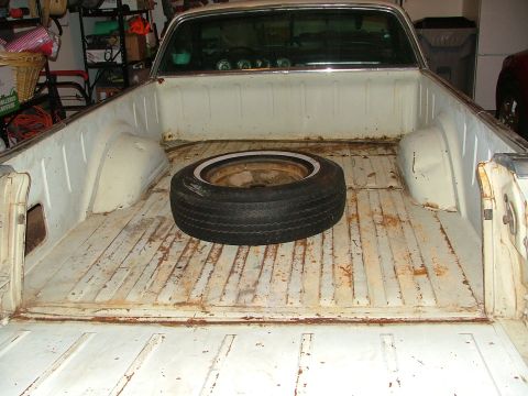 1969 Ford Ranchero - The interior of a pickup truck bed shows a spare tire and signs of wear and tear.