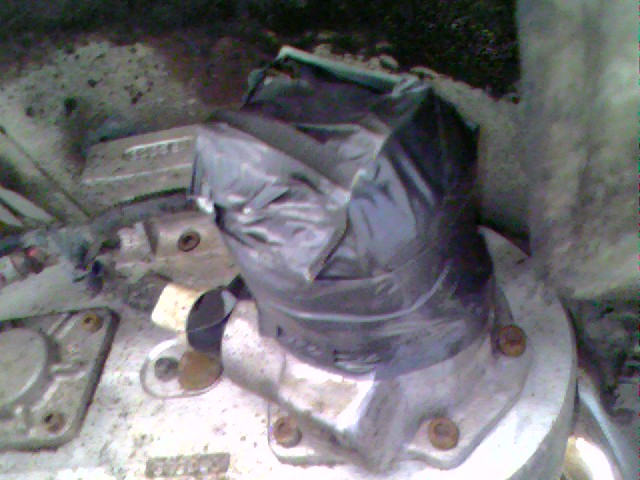 close-up of a metal part covered in a black plastic bag, bolted to something else