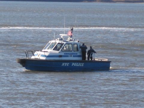 1991 Ford LTD Crown Victoria - A police boat with "NYC POLICE" written on its side cruises through the water.