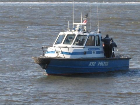 1991 Ford LTD Crown Victoria - A New York City police boat cruises on the water, identified by "NYC POLICE" on its hull.