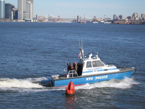 1991 Ford LTD Crown Victoria - NYC Police boat navigates the water with the Brooklyn Bridge and Manhattan skyline visible.