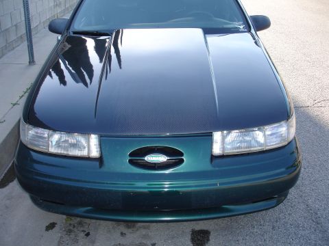 1993 Ford Taurus - A green car with a carbon fiber hood is shown from the front, an oval grille with a Yamaha logo.