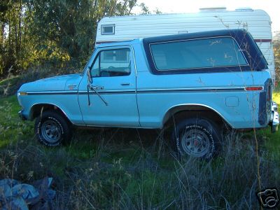 1979 Ford Bronco - A blue 1978 Ford Bronco is parked next to a white camper trailer in a grassy field.