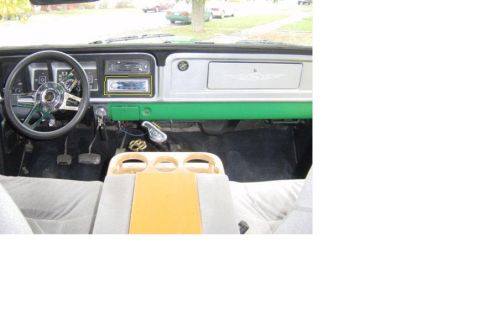 1979 Ford Bronco - The interior of a 1979 Ford Bronco features a green dashboard, custom center console, and aftermarket steering wheel.