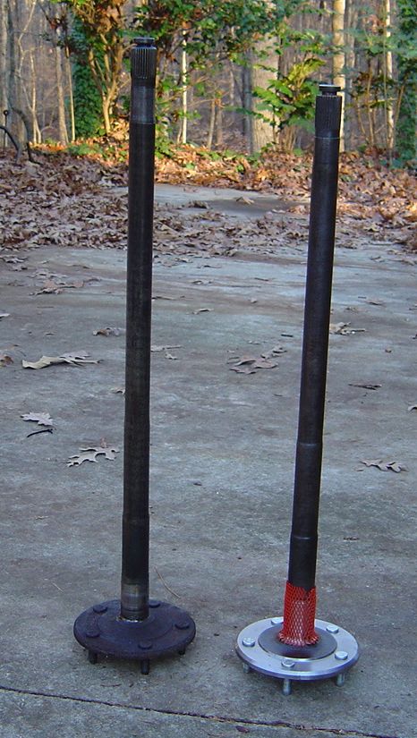 1986 Ford Bronco - Two axle shafts are displayed outdoors on a concrete surface, with one shaft a red protective covering.