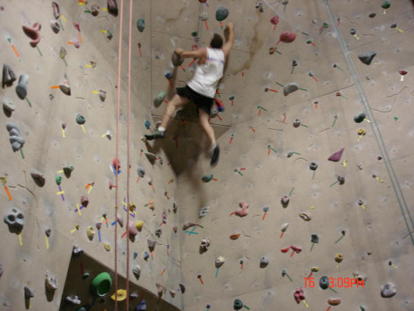 Person climbing an indoor rock wall with colorful holds