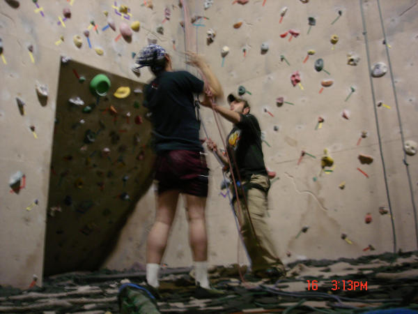Indoor climbing wall with colorful holds, two climbers, and a timestamp in the corner