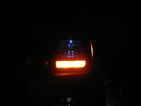 1986 Ford Bronco - The rear light assembly of a vehicle glows in the dark, showing the brake light and turn signal.