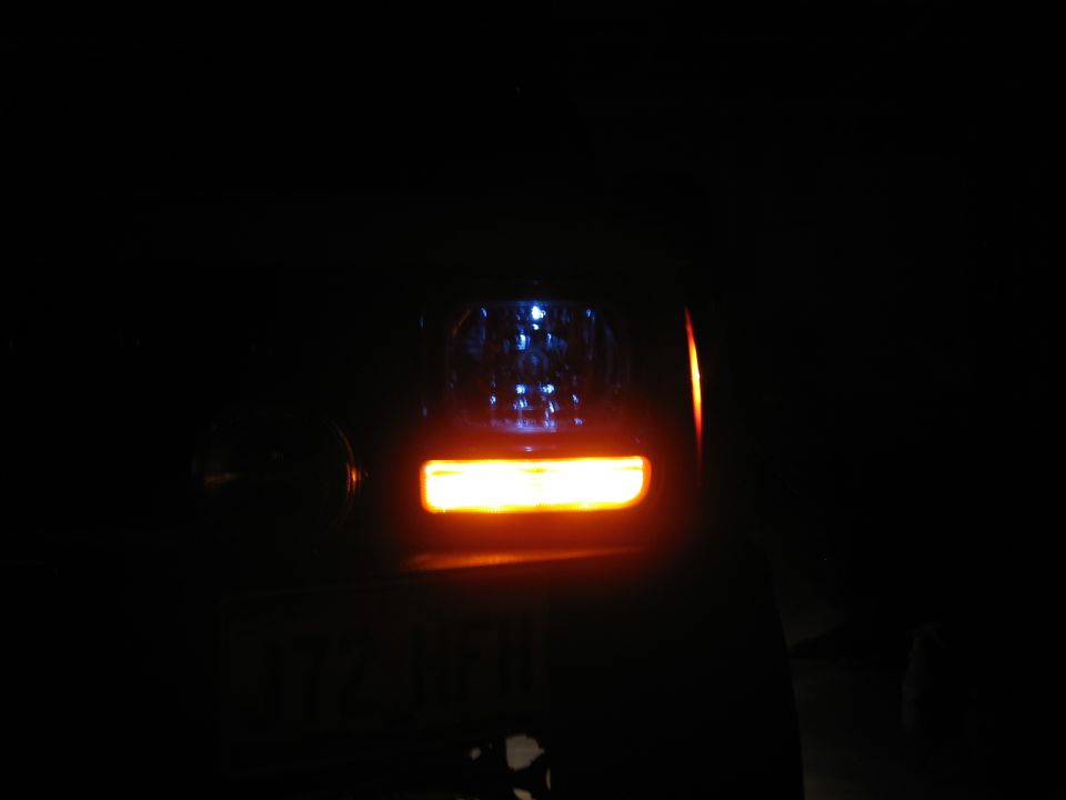 Close-up of a vehicle's illuminated taillight and turn signal at night