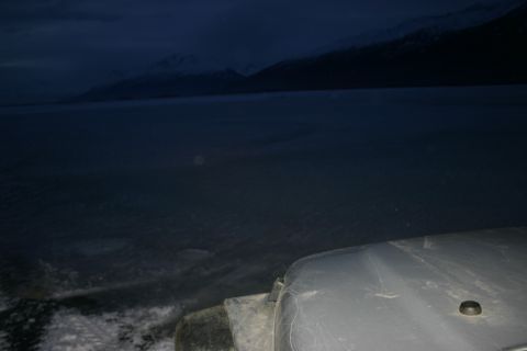 2003 Jeep TJ - A Jeep's hood and tire are visible in the foreground, set against a dark, icy landscape with mountains.