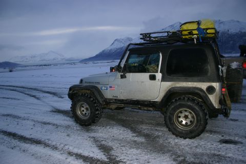 2003 Jeep TJ - Silver 2003 Jeep TJ Rubicon with roof rack and yellow cargo bag parked on a snowy road.