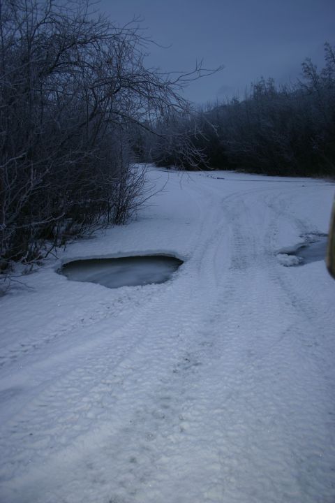2003 Jeep TJ - Winter scene on a snowy road with ice and tire tracks.