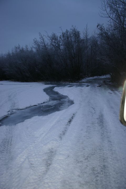 2003 Jeep TJ - Driving on a partially frozen road through a wooded area during twilight.