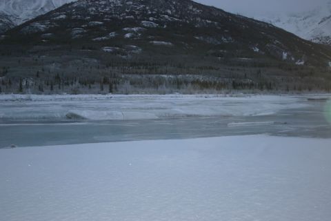 2003 Jeep TJ - A winter scene shows a frozen river in the foreground, with snow-covered trees and mountains in the background.