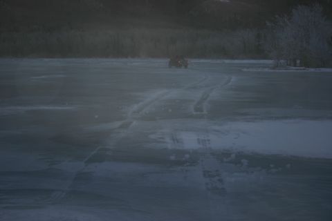 2003 Jeep TJ - A red SUV drives across a frozen landscape, leaving tire tracks behind.