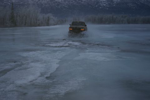 2003 Jeep TJ - A Jeep Wrangler drives through icy water with mountains in the background.