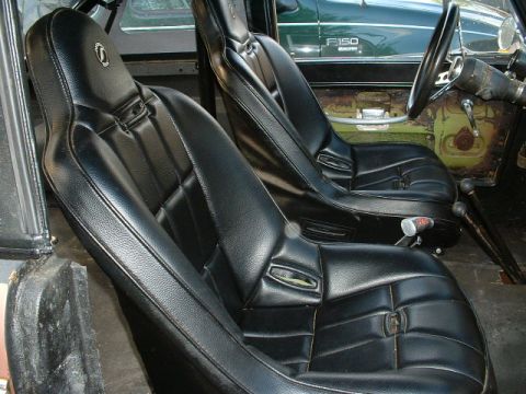 1995 Ford Bronco - Interior view of black bucket seats, with a green Ford F-150 truck seen through the side window.