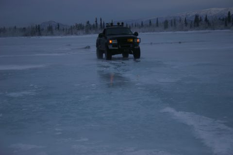 2003 Jeep TJ - A black SUV drives across a frozen landscape under a twilight sky.