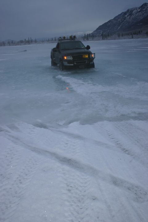 2003 Jeep TJ - Pickup truck navigates across a frozen surface under a cloudy sky.