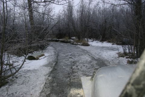 2003 Jeep TJ - A silver vehicle navigates a frozen, icy path through a snow-covered forest during winter.