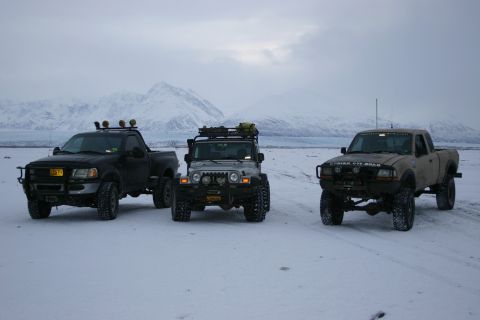 2003 Jeep TJ - Three off-road vehicles are parked in a snowy area with mountains and a glacier visible in the distance.