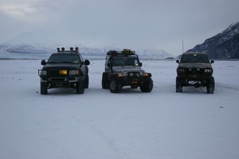 2003 Jeep TJ - Three off-road vehicles are parked in a vast, snow-covered area with mountains in the background.