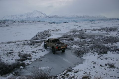 2003 Jeep TJ - Pickup truck navigates an icy path with a glacier and mountains in the distance.