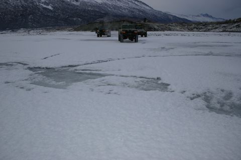 2003 Jeep TJ - Multiple SUVs traverse a frozen, snow-covered terrain under a cloudy sky.