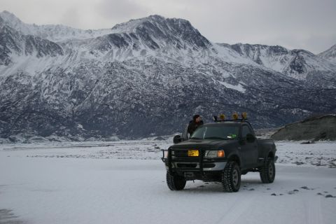 2003 Jeep TJ - A black pickup truck is parked in a snowy landscape with large mountains in the background.
