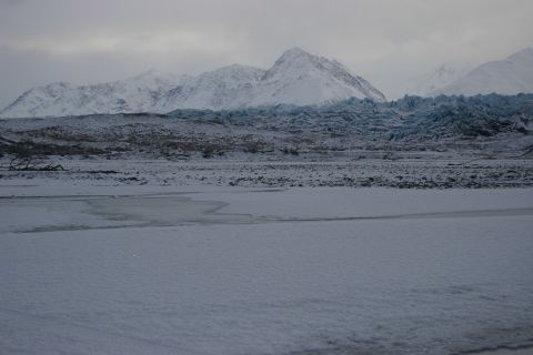 2003 Jeep TJ - A vast, snow-covered landscape stretches towards mountains, with a prominent glacier in the mid-ground under an overcast sky.