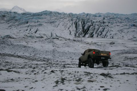 2003 Jeep TJ - A pickup truck navigates a snowy landscape with a massive glacier looming behind it.