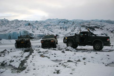 2003 Jeep TJ - A 2003 Jeep TJ and two trucks navigate a snowy glacial landscape under an overcast sky.