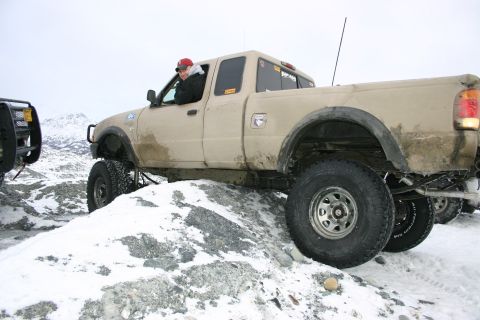 2003 Jeep TJ - Pickup truck navigating challenging snowy terrain with another vehicle nearby.