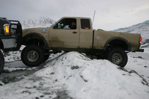 2003 Jeep TJ - Two trucks navigate a snowy, mountainous terrain with a glacier visible in the background.