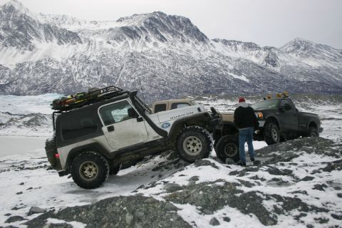 2003 Jeep TJ - A white Jeep Wrangler Rubicon and two other vehicles are parked on a rocky, snow-covered terrain with mountains in the background.