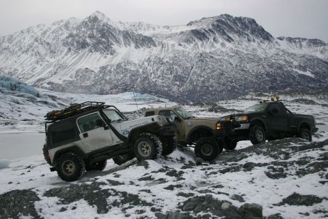 2003 Jeep TJ - A convoy of off-road vehicles, including a white 2003 Jeep Wrangler Rubicon, navigates a snowy, mountainous landscape.