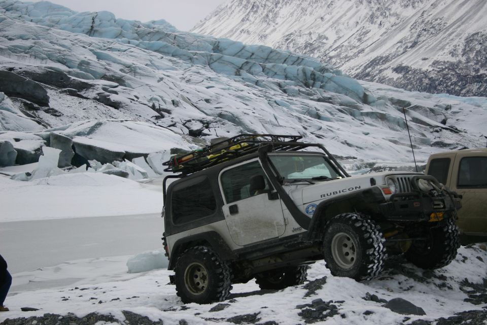 Jeep Wrangler Rubicon parked on snowy ground with glacier in background