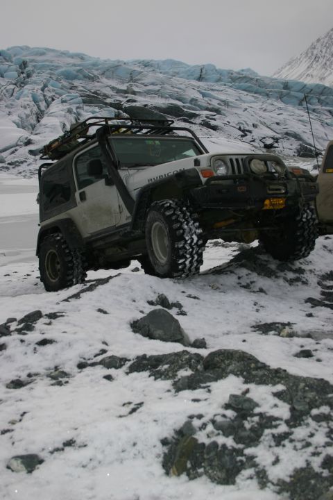 2003 Jeep TJ - A white 2003 Jeep Wrangler Rubicon navigates a snowy, rocky landscape with a glacier in the background.
