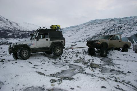 2003 Jeep TJ - Two off-road vehicles, a Jeep TJ and a Ford Ranger, navigate a snowy, icy terrain with a glacier in the background.