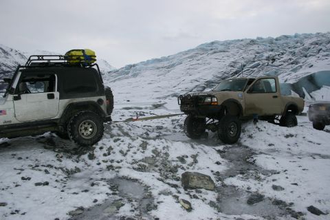 2003 Jeep TJ - A white 2003 Jeep TJ tows a tan Ford Ranger across a snowy, icy landscape with a glacier visible in the background.