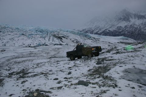 2003 Jeep TJ - Pickup truck navigates snowy terrain near a glacier under a cloudy sky.