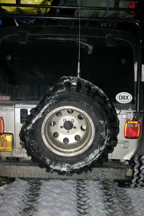 2003 Jeep TJ - A silver 2003 Jeep TJ is seen from the rear in a snowy environment, with a spare tire mounted on the tailgate.