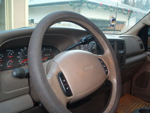 2000 Ford Excursion - The dashboard and steering wheel of a Ford Excursion are visible, with a view of the exterior through the windshield.