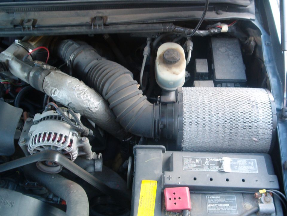 Ford Super Duty engine bay with air filter, alternator, and battery visible