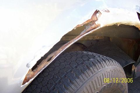 1995 Ford Bronco - The wheel well of a vehicle shows significant rust damage and deterioration.