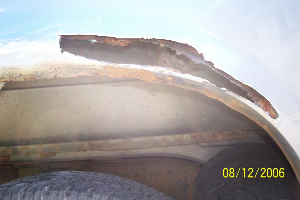Rusted wheel well interior with visible tire and date stamp 08/12/2006
