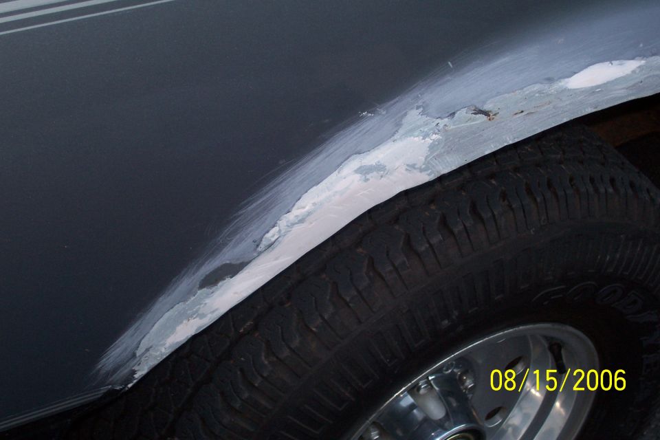 Close-up of body filler being applied to the rear wheel well of a vehicle