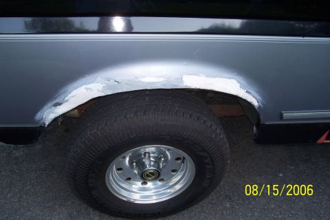1995 Ford Bronco - The rear wheel well of a vehicle shows signs of rust repair with applied body filler and primer.
