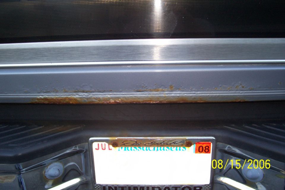 Rear bumper area with rust on the trim above the license plate. Massachusetts plate visible