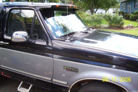 1995 Ford Bronco - The side profile of a two-tone Ford Bronco is visible, parked in a residential area.